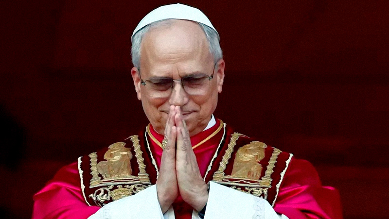 El Papa León XIV, con vestimenta papal, contiene su emoción mientras junta las manos en su primer saludo al mundo católico desde el balcón de la Basílica de San Pedro.